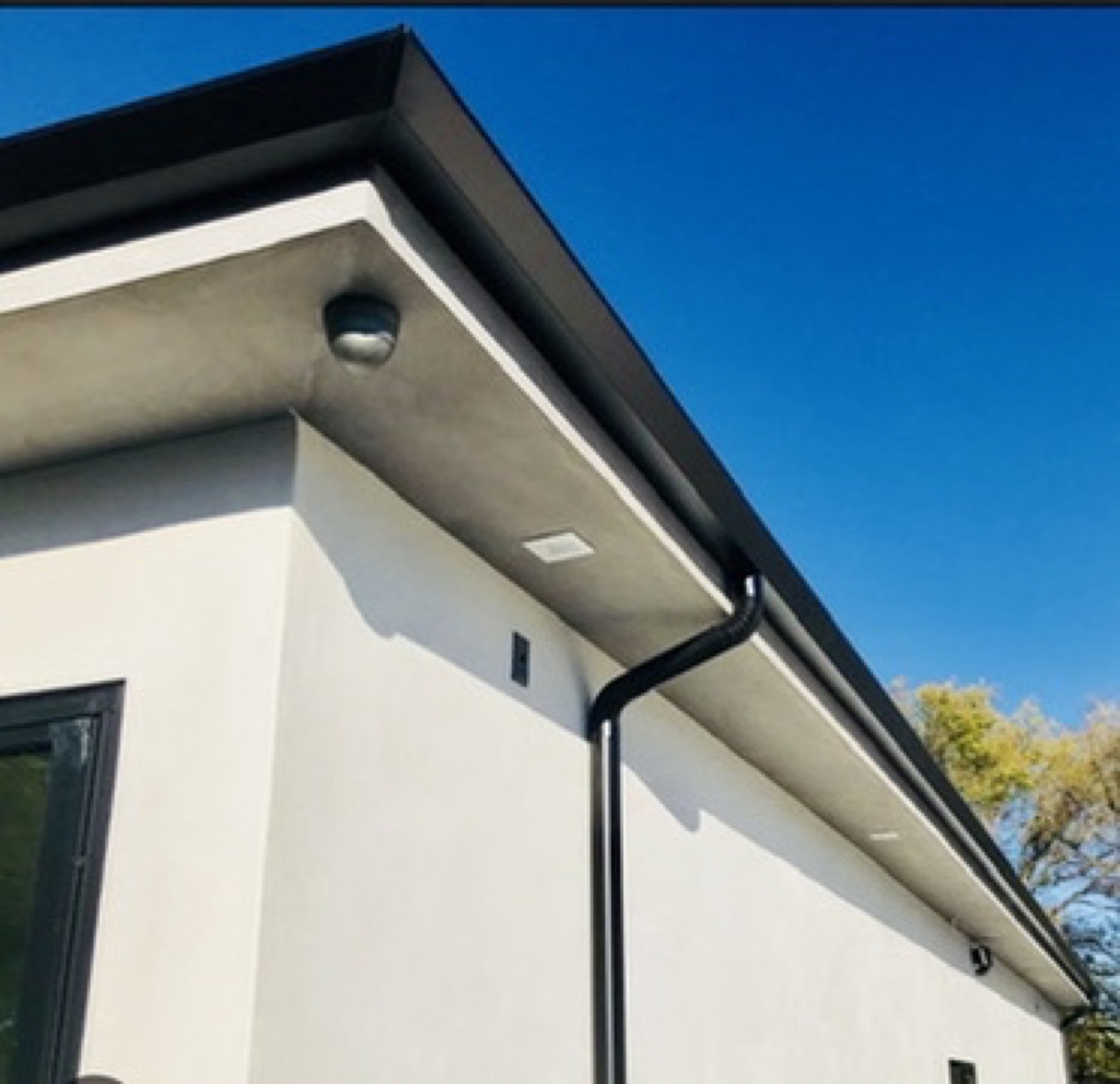 City Seamless straight-face gutter with downspout routing on a modern roofline.